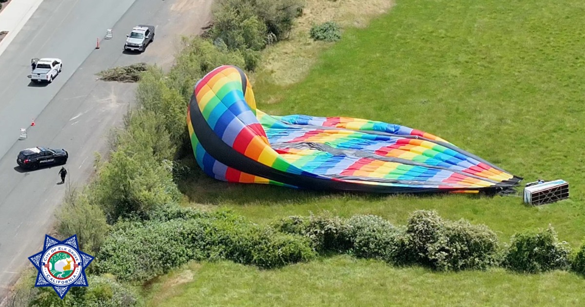 A partially deflated hot air balloon is seen in a field from the air after the pilot made a forced landing.