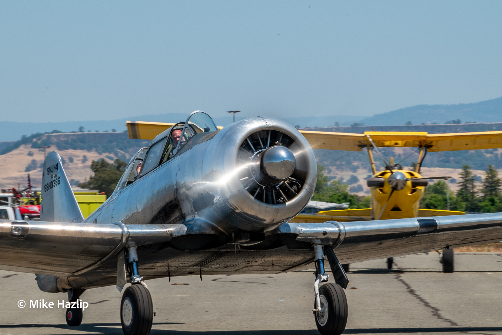 A T-6 Texan taxies past a yellow biplane at the 2023 Oroville fly-in.